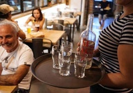 Una camarera sirve agua a unos clientes.