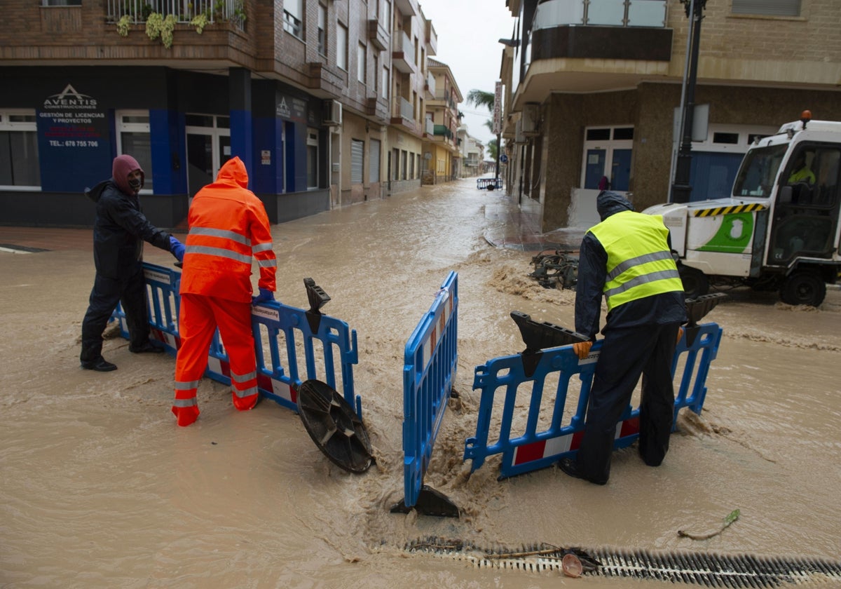 Varios operarios señalizan las alcantarillas en una calle de Los Alcázares ante unas inundaciones en 2020.