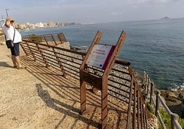 Un vecino en el mirador del Galúa, junto a la barandilla oxidada, y al fondo edificios de La Manga.
