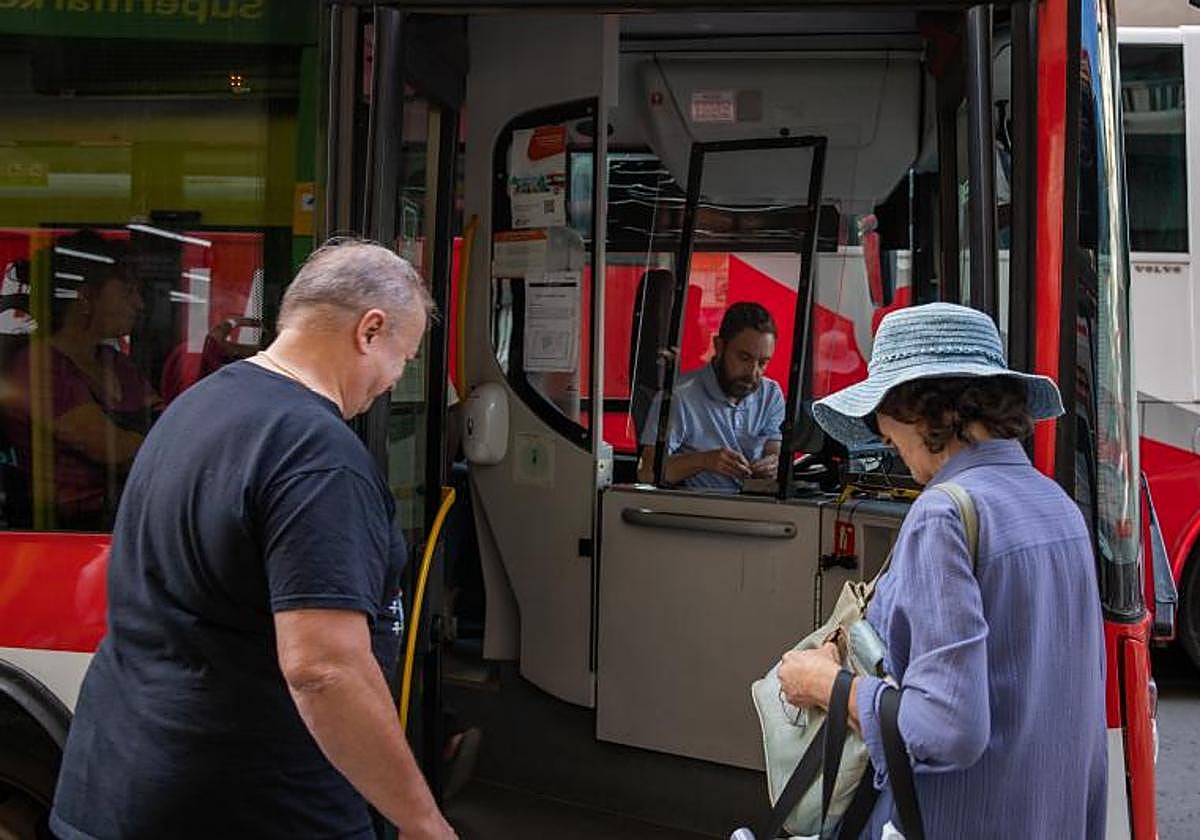 Dos pasajeros toman un autobús en la parada de la calle Ramón Gallud.