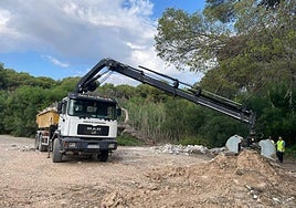 Un camión retira escombros depositados junto a la rambla del río Nacimiento, en Campoamor.