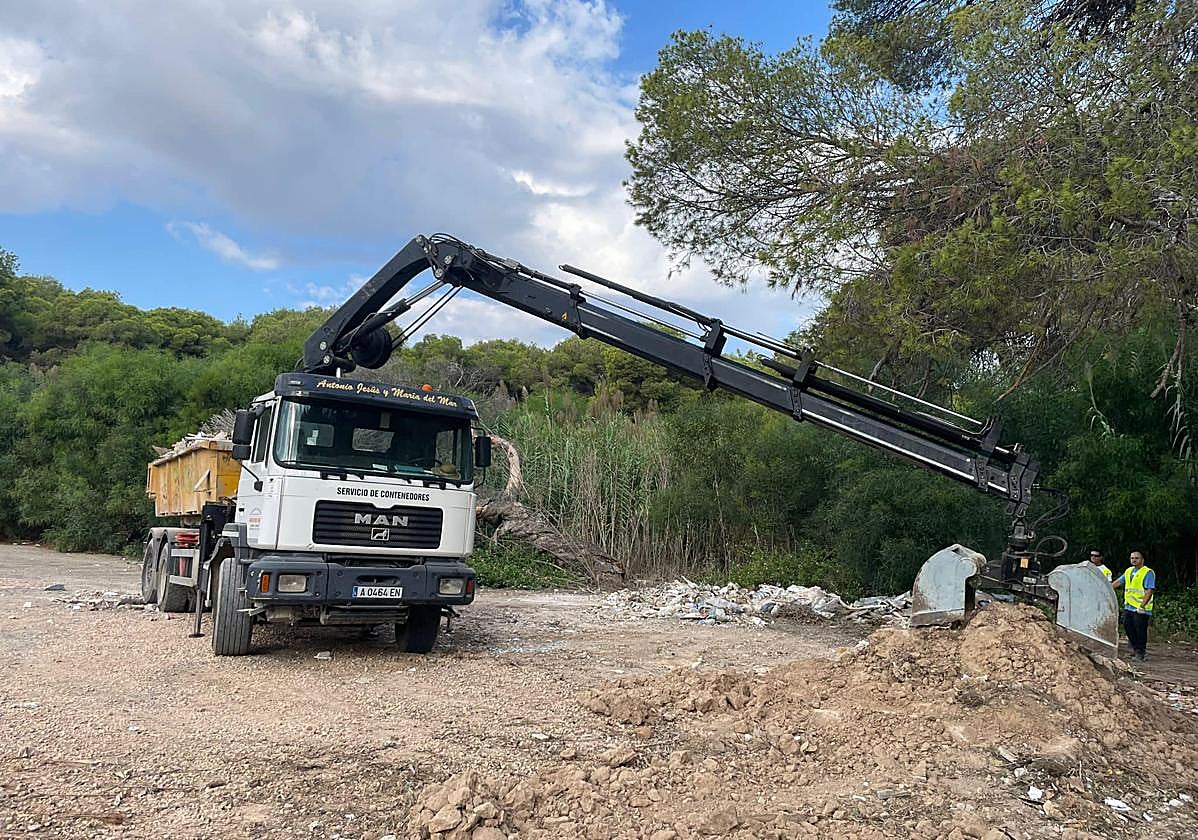Un camión retira escombros depositados junto a la rambla del río Nacimiento, en Campoamor.