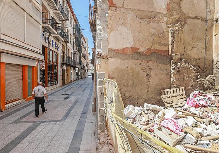 En la calle Mayor hay dos solares vacíos, uno de ellos lleno de enseres y basura.