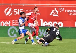 Kenneth, novedad en el once inicial del Real Murcia ante el Sabadell, intenta llegar al balón antes que Ortega, portero rival.