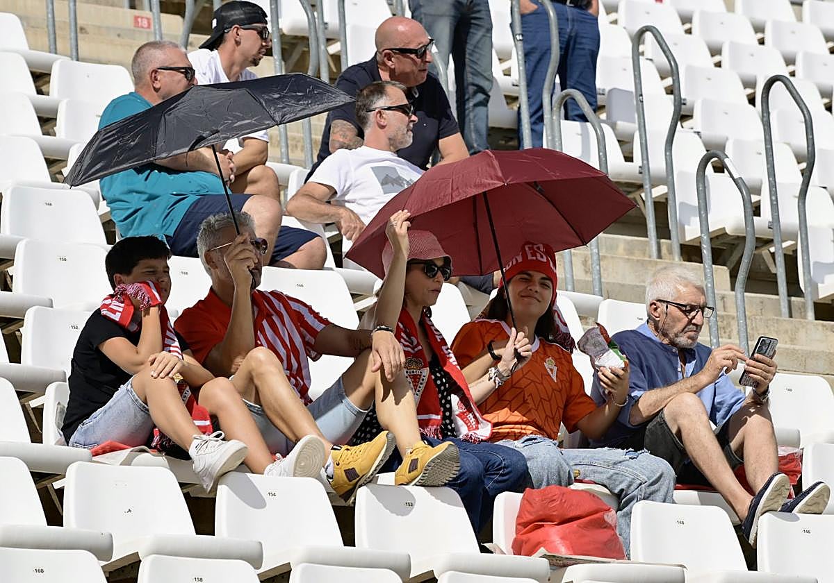 Aficionados se protegen del sol con paraguas, este domingo en el Real Murcia-Alcorcón.