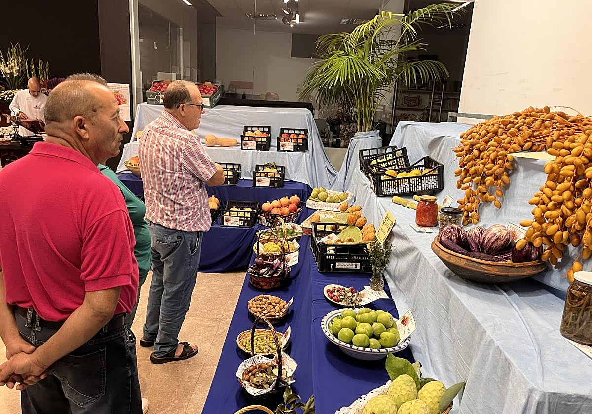 Unos vecinos observan las exposiciones de frutas de la feria.