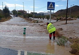 Un técnico de emergencias corta el tráfico en una calle inundada.