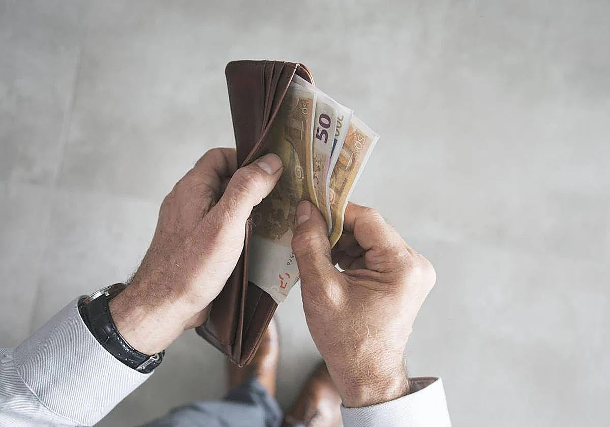 Un hombre saca dinero de la cartera.