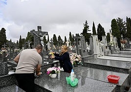 Vecinos limpian una tumba en el cementerio municipal.