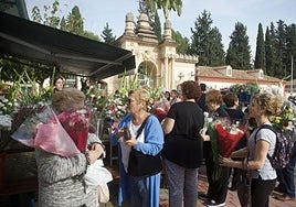Varias personas compran flores a la entrada del cementerio Nuestro Padre Jesús, en Espinardo, por el Día de Todos los Santos.