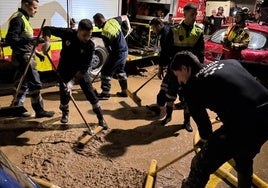 Policías locales de Murcia limpian el barro en una de las calles de Algemesí.