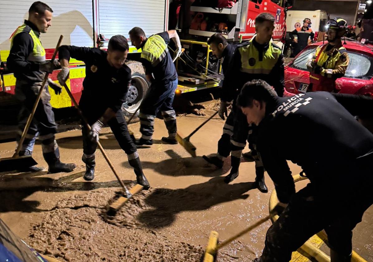 Policías locales de Murcia limpian el barro en una de las calles de Algemesí.