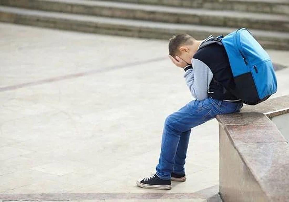 Un niño llora en el patio de un colegio.