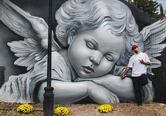 David Flores, junto al mural pintado en la tapia del cementerio.