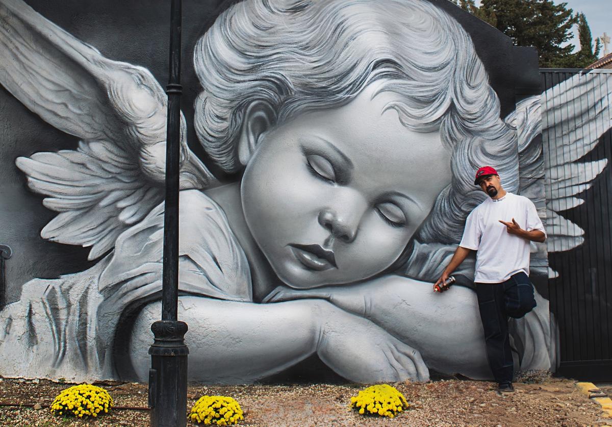 David Flores, junto al mural pintado en la tapia del cementerio.