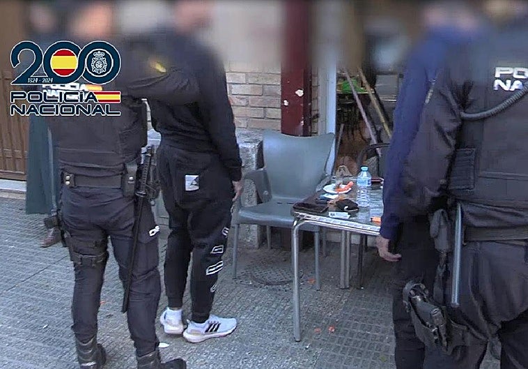 Agentes de la Policía Nacional inspeccionan a dos personas en un local.