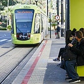 Varias personas esperan la llegada del tranvía de Murcia en una parada.
