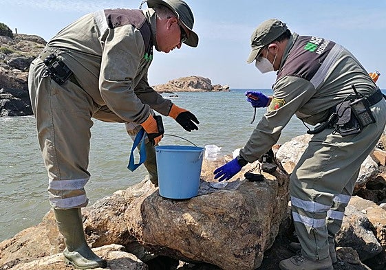 Dos agentes medioambientales toman muestras de un vertido producido en la costa regional, en una imagen de archivo.