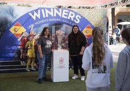 Dos aficionadas se fotografían con la Copa del Mundo ganada por España el año pasado.