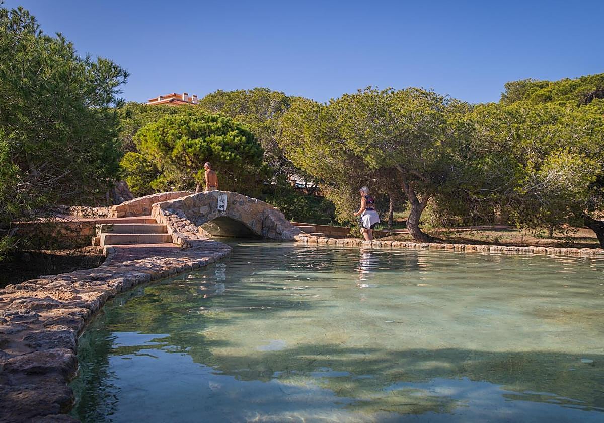 Dos turistas pasean junto al canal de agua que atraviesa el parque.