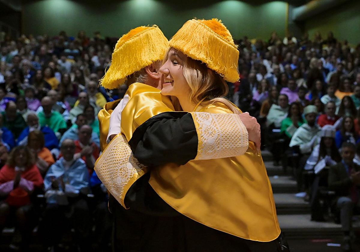Una de las nuevas doctoras se abraza a uno de sus docentes tras ser investida.