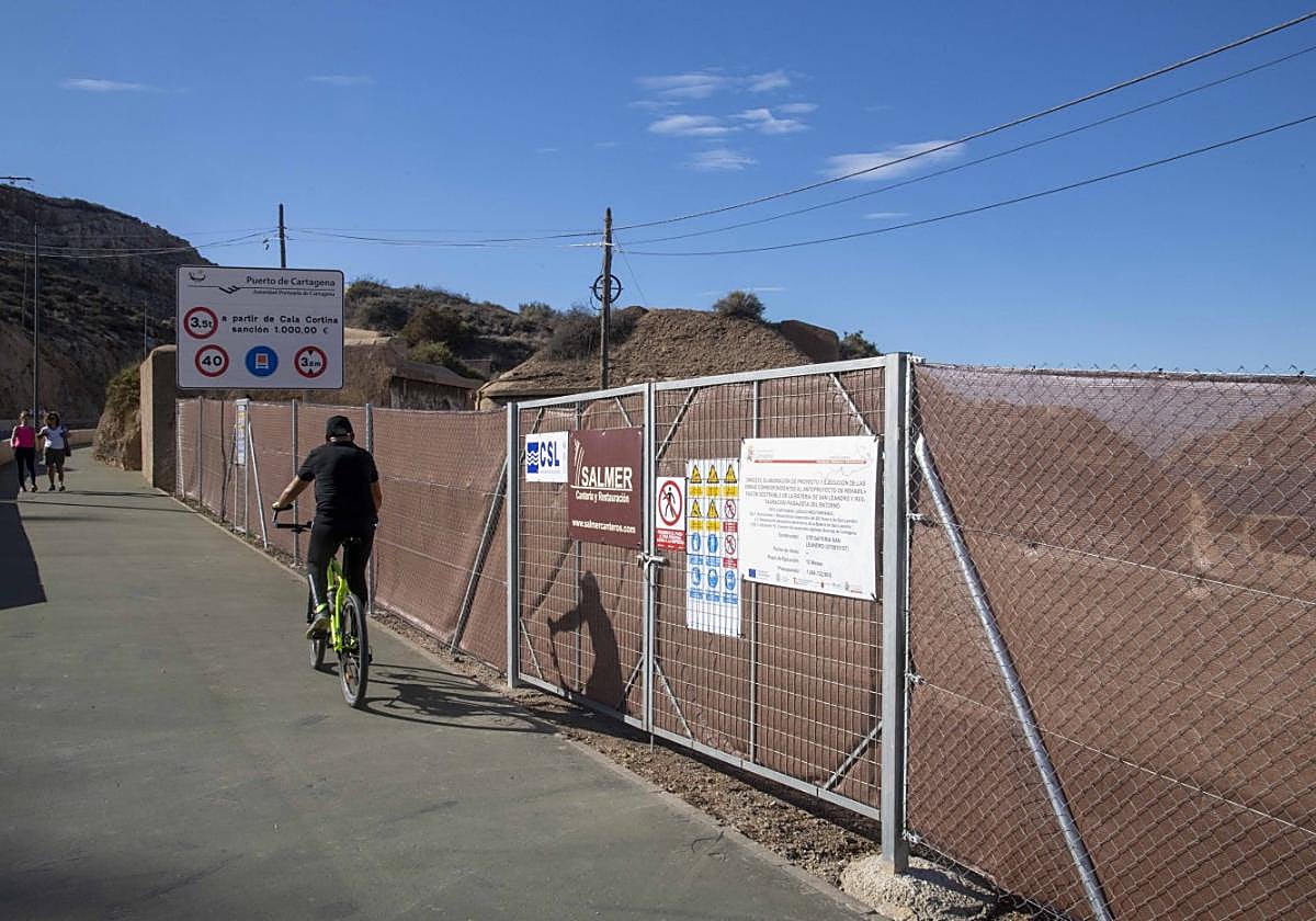 Un ciclista circula junto al vallado de obras de la batería de San Leandro.