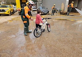 Un brigada forestal del dispositivo de la Comunidad, con un niño en bicicleta en Paiporta.