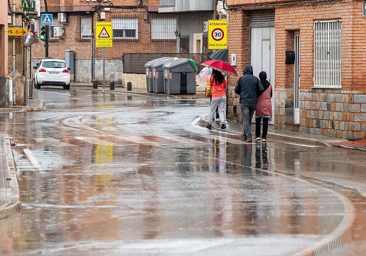 Peatones cruzan la calle resguardándose de lluvia.