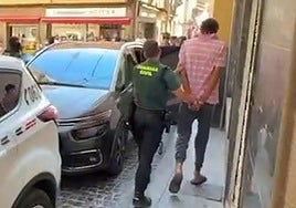 Un Guardia Civil lleva esposado al detenido.