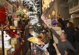 La carroza del Rey Gaspar, a su paso por la calle del Carmen repleta de público con conos pidiendo los regalos que el mago y sus pajes reparten.