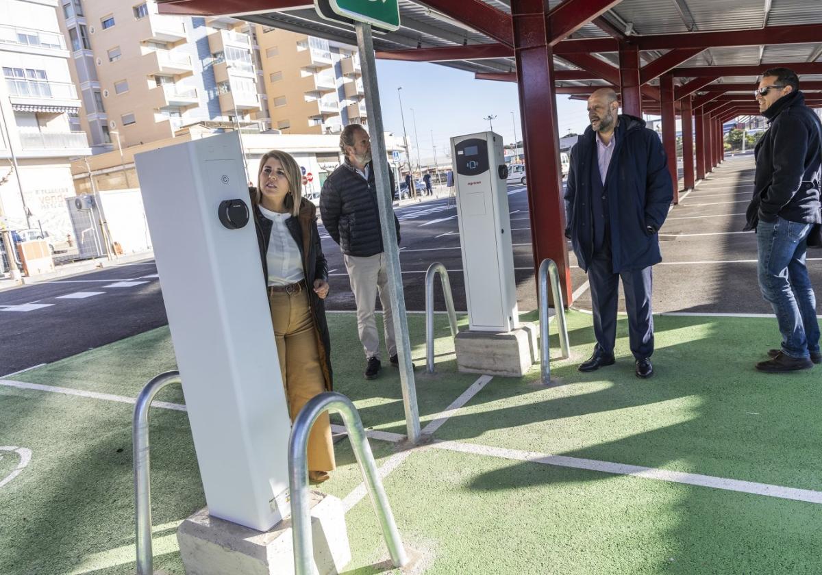 La alcaldesa, acompañada por Ortega y técnicos, mira un poste de recarga eléctrica del parking.