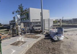 Colegio de Educación Infantil y Primaria La Aljorra, con la puerta cerrada y en cuyo exterior realizan labores de mantenimiento en un entronque de agua potable.