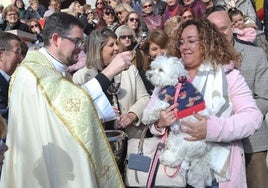 El párroco de San Antón bendice un perro en presencia de vecinos y autoridades locales.