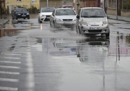 Coches circulan por una calle de Murcia encharcada por la lluvia, en una imagen de archivo.