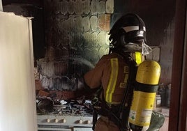 Un bombero apaga el incendio de la vivienda de Lorca, este viernes.