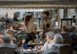 Dos trabajadores de hostelería atienden mesas en una terraza de Murcia.