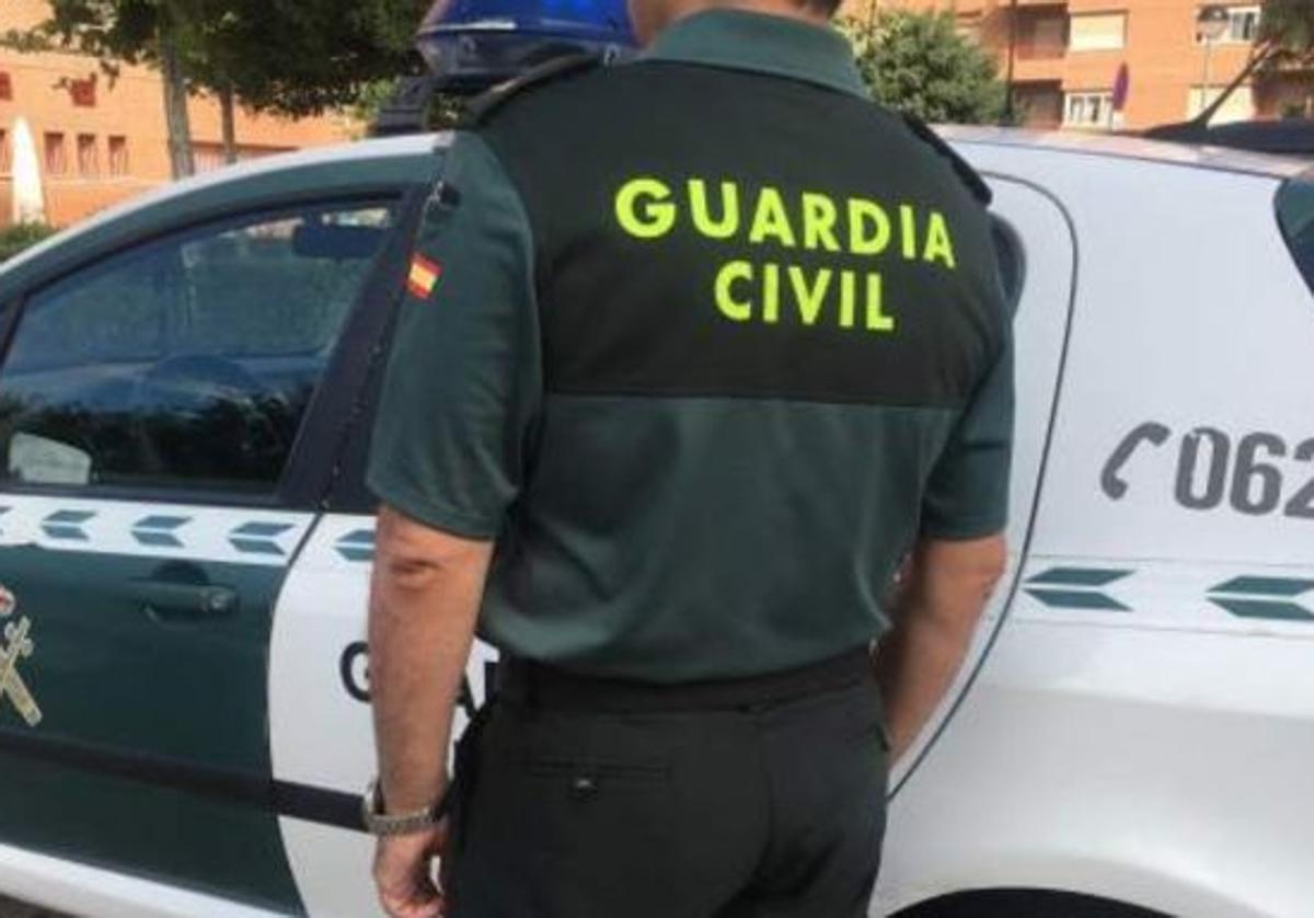 Un agente de la Guardia Civil junto a su vehículo.