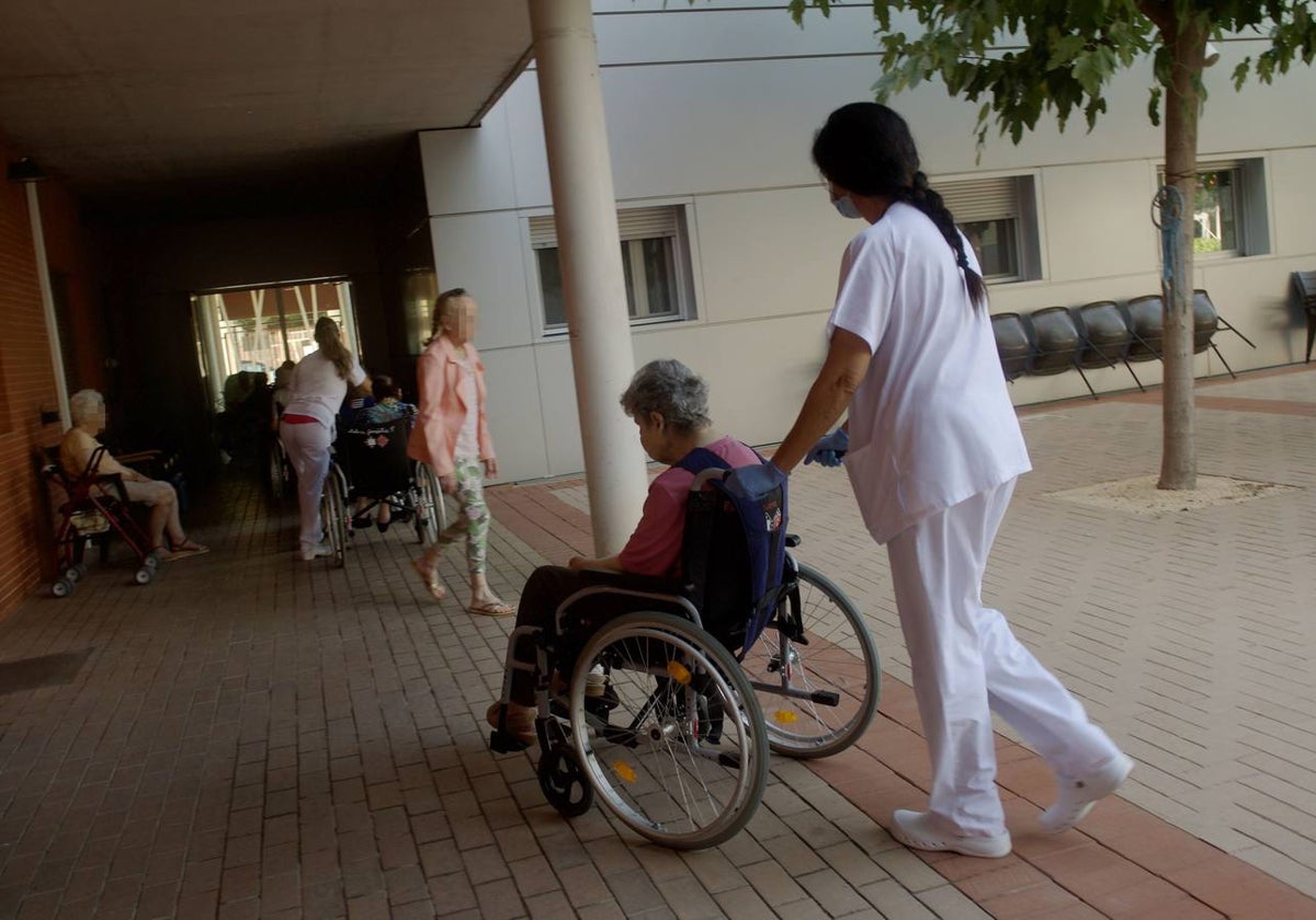 Una sanitaria traslada a una mujer en situación de dependencia en una residencia de Murcia.