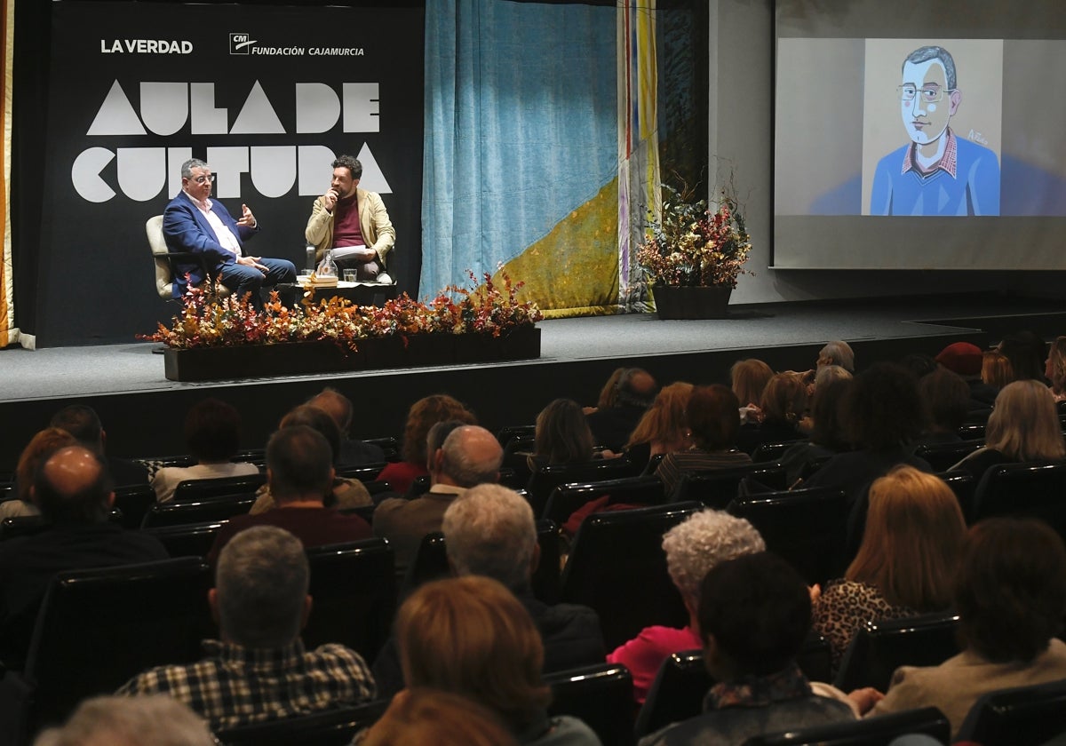 Aitor Larrabide en el salón de actos de la Fundación Cajamurcia, con el retrato que le realizó Arturo Pérez en pantalla.