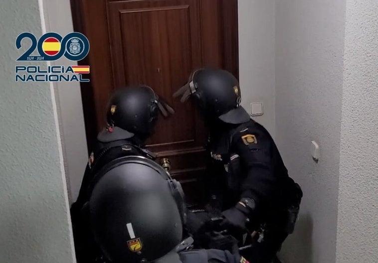 Dos agentes tratan de abrir una puerta para realizar un registro.