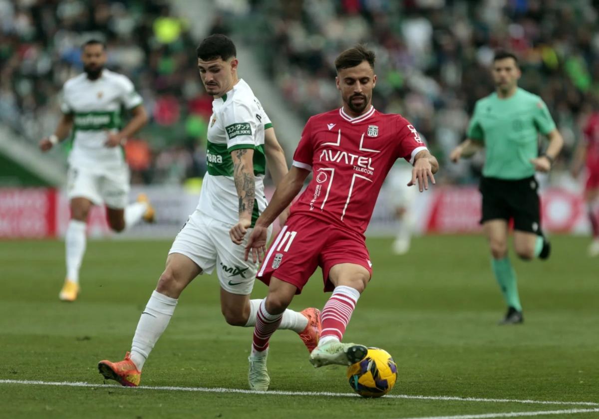 Óscar Clemente conduce el balón en el Martínez Valero perseguido por el delantero Agustín Álvarez.