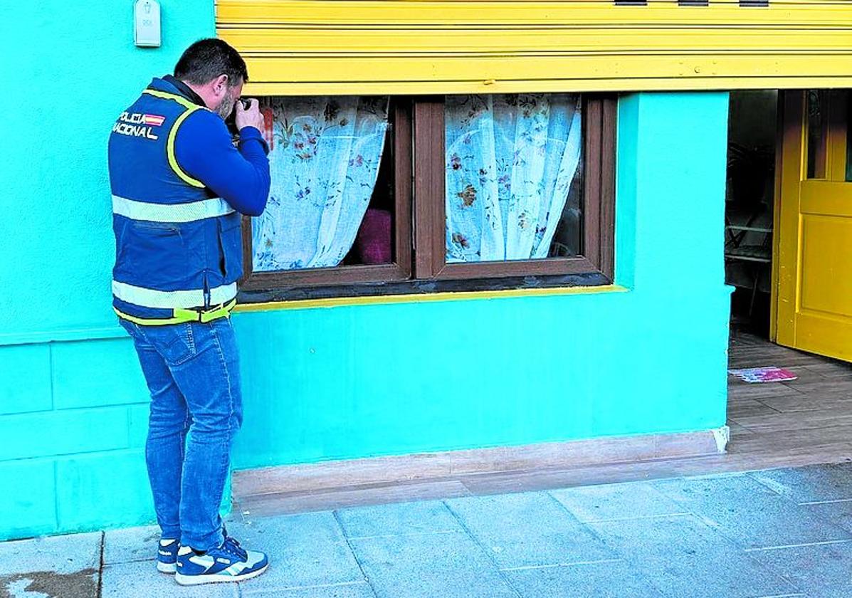 Un agente de la Policía Nacional toma imágenes de la ventana por la que entraron a robar al bar La Malaka Café el pasado miércoles.