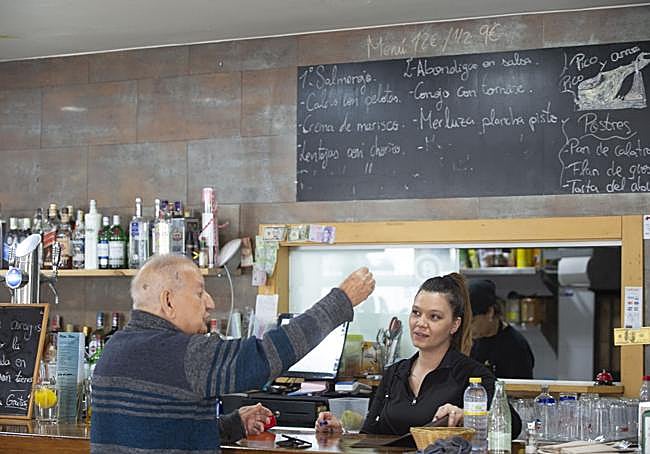 Un cliente de Pico Pico y Arroz. Al fondo, platos y precios del menú del día.