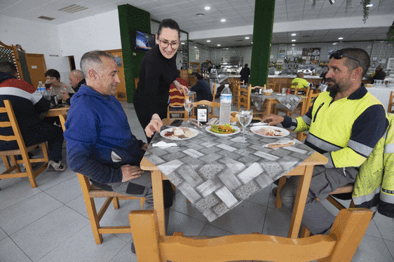 Una camarera del restaurante Las Palmeras IV, en el Polígono Industrial Oeste, sirve el menú del día a dos clientes.