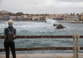 Una mujer observa la fuerza de las olas desde el paseo de Cabo de Palos.