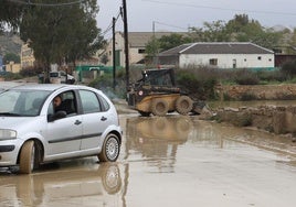 Un coche circula por una carretera llena de barro en Lorca.