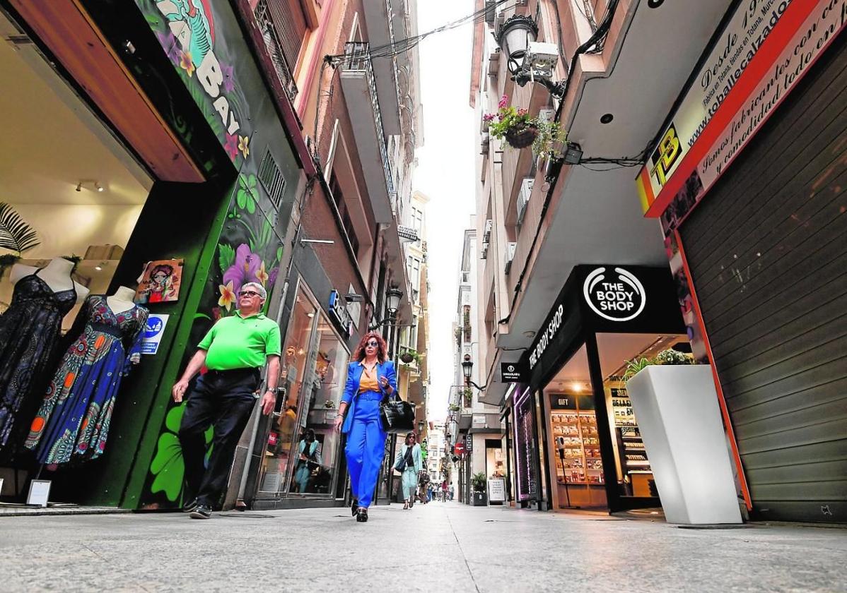 Varios viandantes pasean entre comercios situados en la céntrica calle Platería de Murcia.