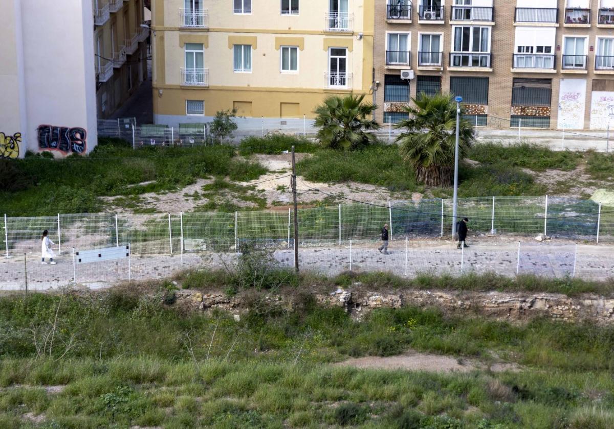 Tres personas transitan por la calle Morería Baja, cuyos solares, con maleza desde hace días, han reverdecido con las últimas lluvias.