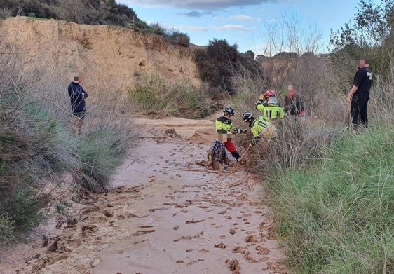 Los bomberos ayudan al hombre a salir del barro.