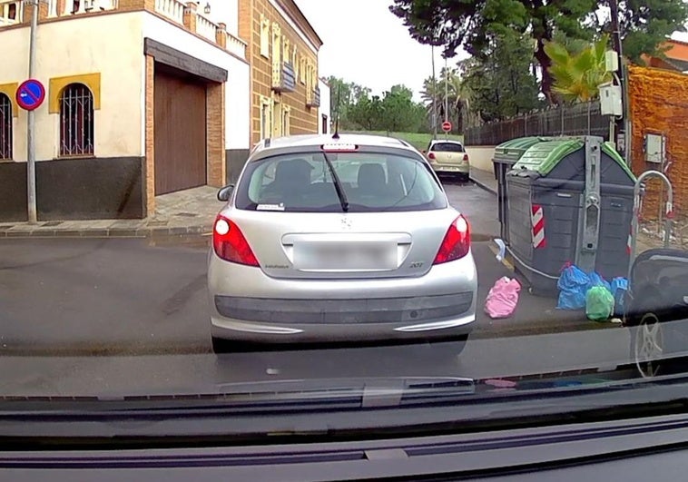 Un conductor arroja una bolsa de basura, desde el interior de su vehículo, en el barrio de Los Dolores de Cartagena.